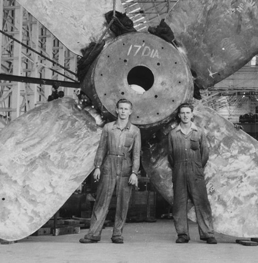 Historic black and white image of men with ship propeller in the Turbine shop in the 1940s on Cockatoo Island.